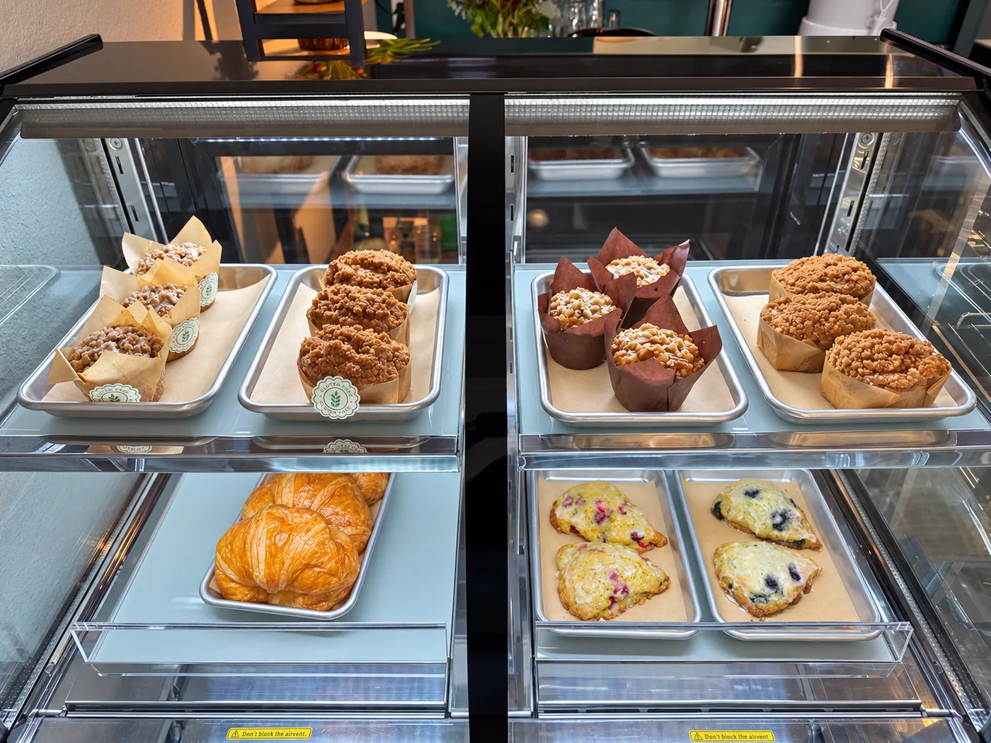 Pastry case with crumb-topped muffins, croissants and berry scones